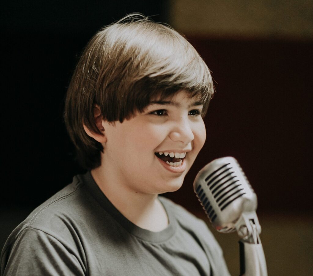 A young boy smiling into a microphone