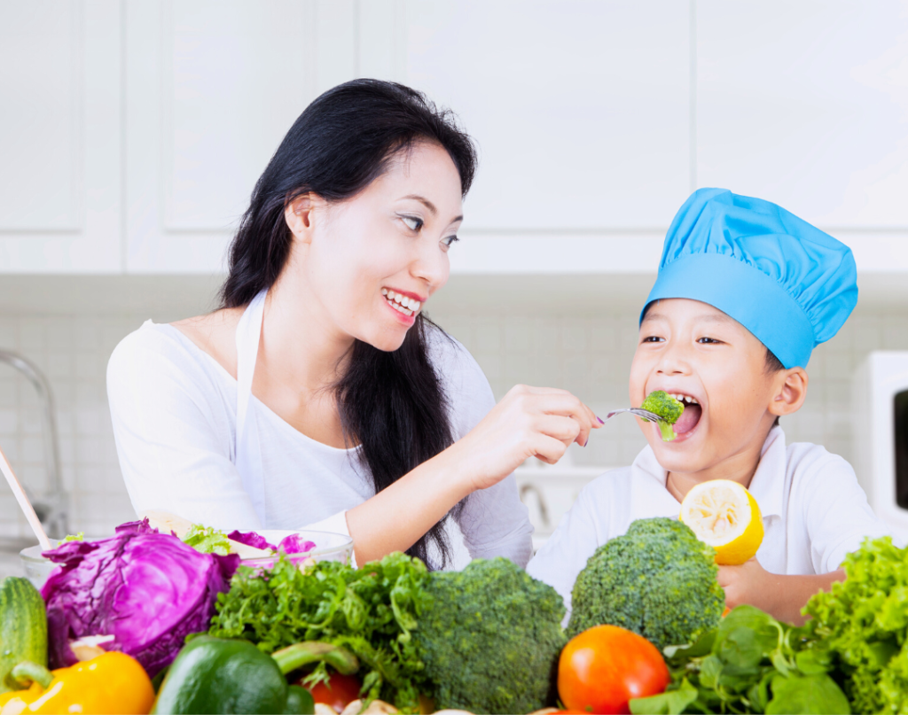 child with vegetables eating broccoli