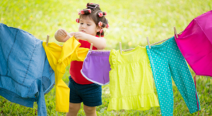 small child using clothespin to hang laundry