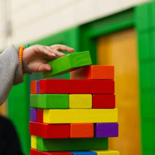 Close up of child's hand stacking colorful wooden blocks